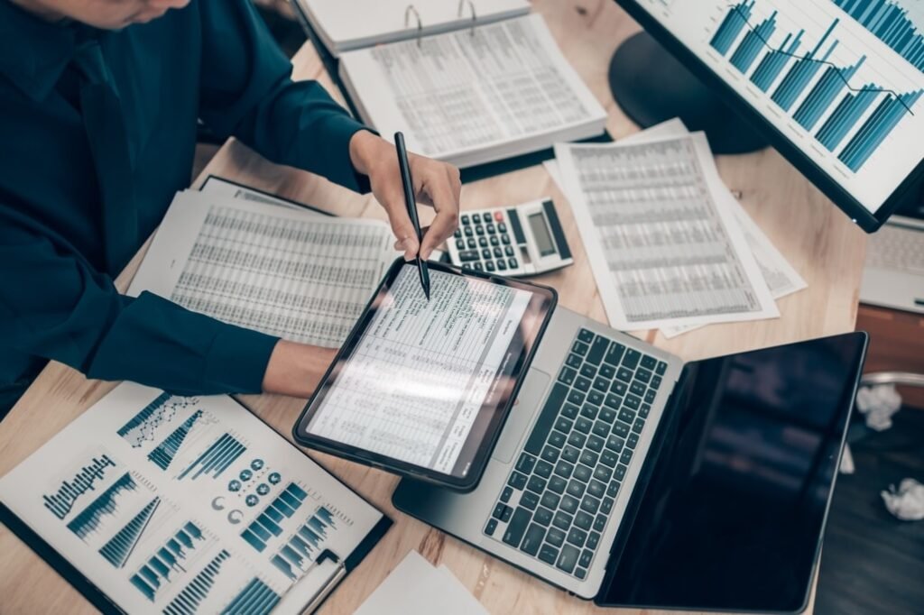 Businessman analyzing financial data on a tablet and laptop, focusing on business credit repair strategies.